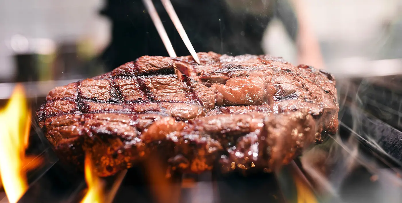 Angebratenes Steak wird mit einem Steak-Gabel über einem Feuer gehalten